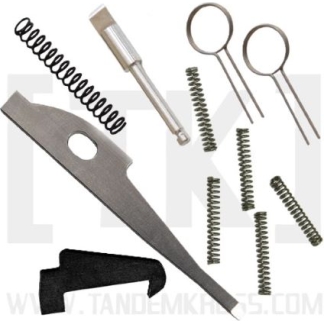 Assorted firearm maintenance tools: springs, punches, a disassembly blade, and small pins laid out on white background.