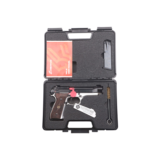 Pistol-shaped tool with brown handle and red trigger in a foam-lined black carrying case, alongside a small white tool and wrench, plus an orange manual.