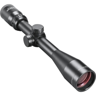 Close-up of a black rifle scope with elevation and windage knobs and a large objective lens, viewed from the side