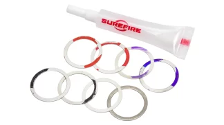 White squeeze tube labeled SUREFIRE beside a pile of silver metal rings with red and purple paint marks.