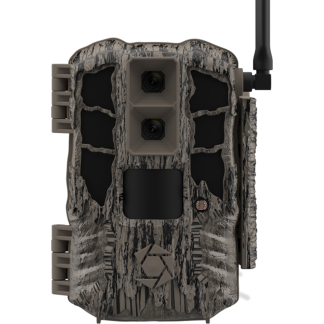 Trail camera in camouflage with dual lenses and antenna, mounted for wildlife monitoring.