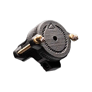 Close-up of a small black circular dial with a central hole, two brass adjustment screws, and a mounting base.